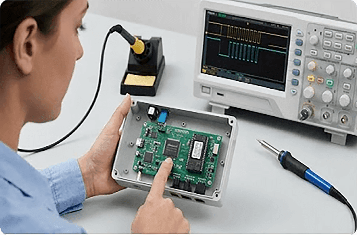 Engineer debugging an embedded board with an oscilloscope